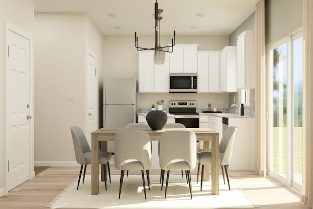 402 Redwood St N, Cambridge, MN 55008 - kitchen featuring appliances with stainless steel finishes, a chandelier, light wood-type flooring, white cabinets, and pendant lighting