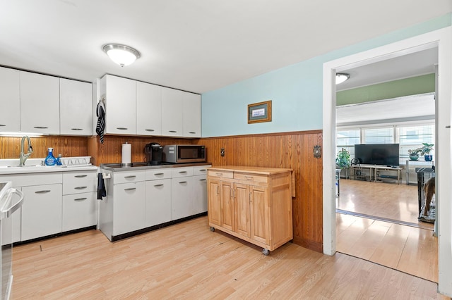 1391 Main St, Saint Joseph Twp, WI 54082 - kitchen featuring stainless steel microwave, light wood-style floors, a wainscoted wall, white cabinets, and wooden walls