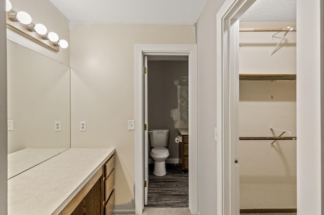 6007 Covington Ter, Minnetonka, MN 55345 - bathroom featuring toilet, vanity, a spacious closet, and wood finished floors