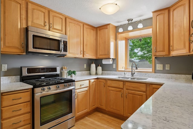 2452 Black Lake Rd, Spring Park, MN 55384 - kitchen featuring appliances with stainless steel finishes, a sink, light stone countertops, light wood-style flooring, and a textured ceiling
