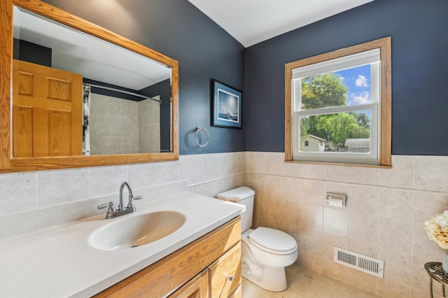 full bath with toilet, vanity, a shower with curtain, tile patterned flooring, and a wainscoted wall