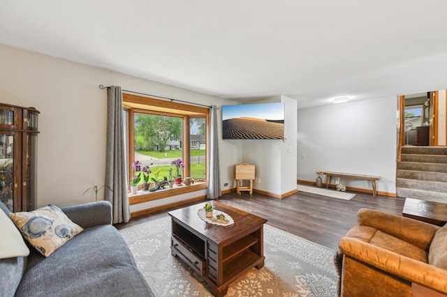 living area with wood finished floors, stairway, and baseboards