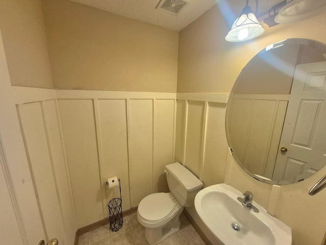15437 Frost Path Unit 1507, Apple Valley, MN 55124 - half bathroom with a sink, toilet, a decorative wall, a wainscoted wall, and tile patterned flooring