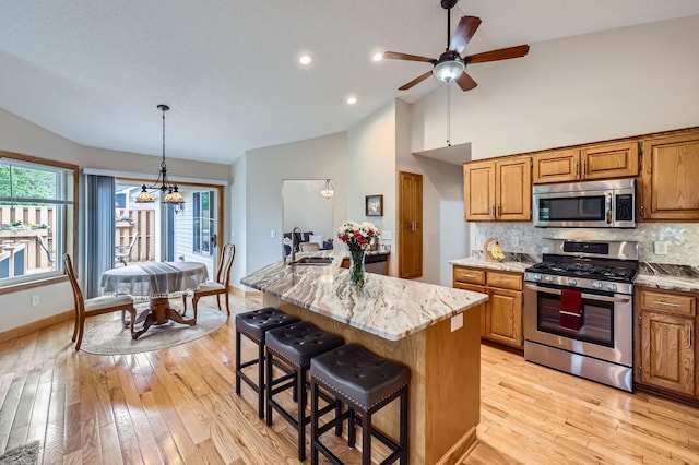 13546 Maryland Ave, Savage, MN 55378 - kitchen with stainless steel appliances, a kitchen bar, brown cabinetry, a ceiling fan, and tasteful backsplash