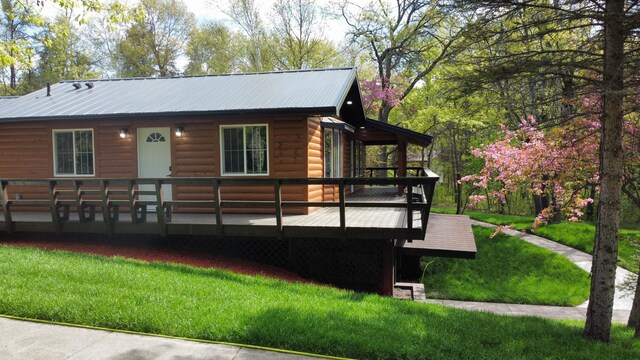 3245 Laketown Rd, Sturgeon Lake, MN 55783 - view of front of house featuring log veneer siding, a wooden deck, a front yard, and metal roof