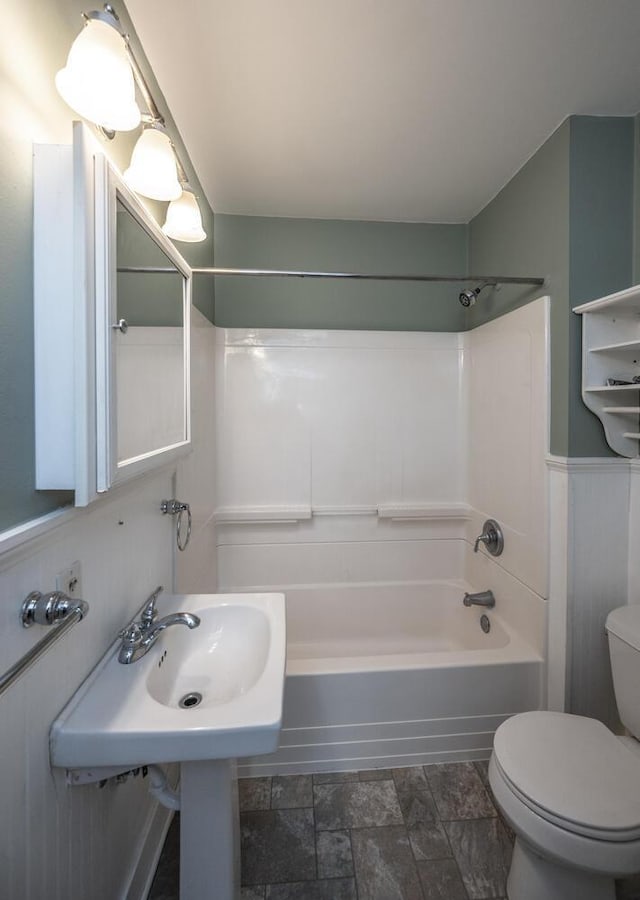 711 2nd St W, Northfield, MN 55057 - full bathroom with toilet, shower / bathtub combination, a wainscoted wall, and stone finish flooring