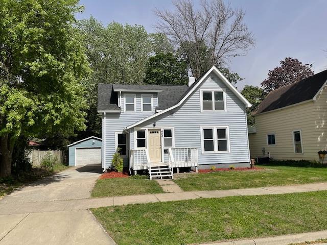 view of front facade featuring an outbuilding, a front yard, a garage, a deck, and a chimney