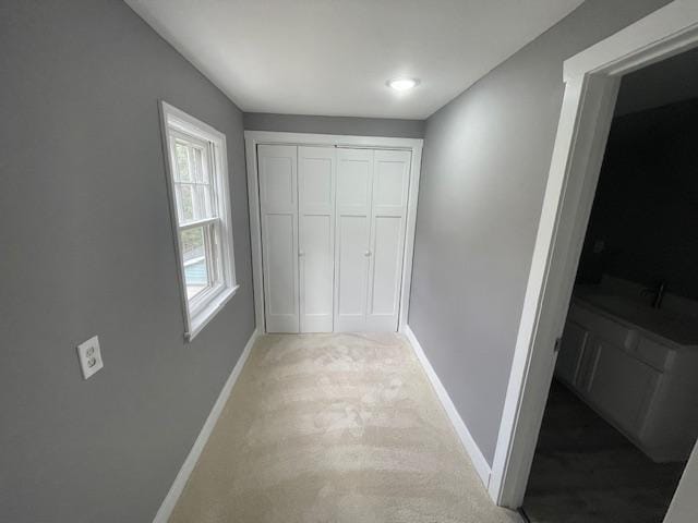 hall with baseboards and light carpet