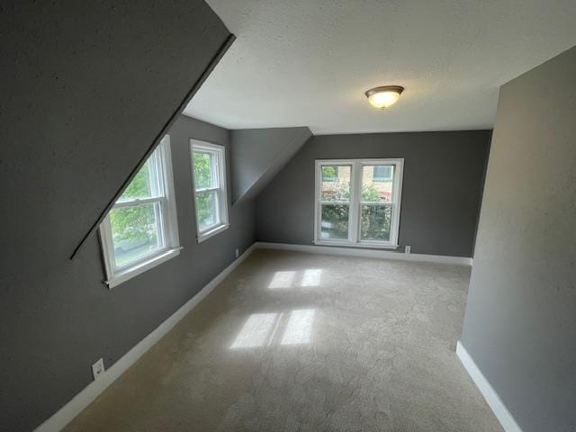 additional living space with plenty of natural light, baseboards, carpet, and vaulted ceiling