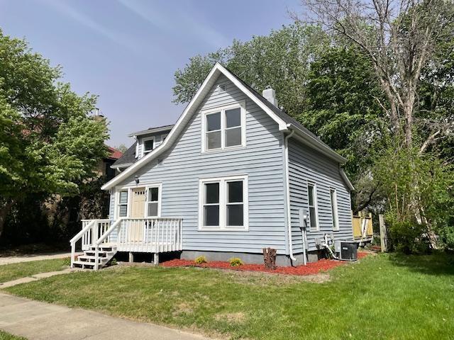 view of side of home with a yard, a chimney, a deck, and cooling unit
