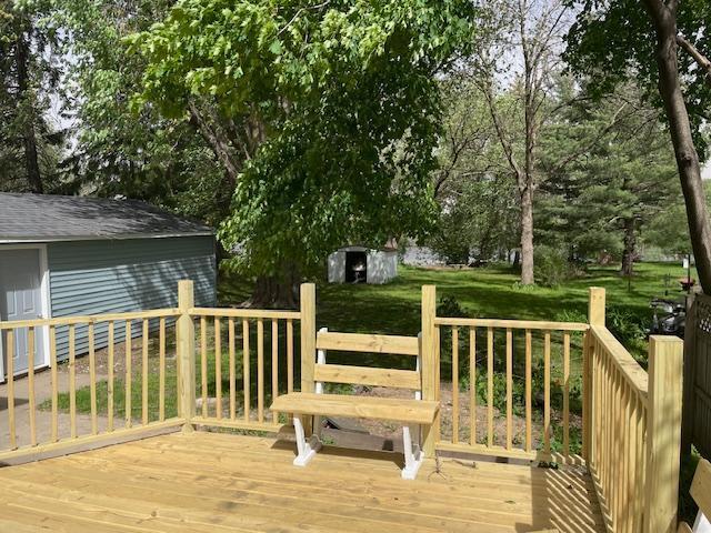 deck with an outbuilding, a storage unit, and view of scattered trees