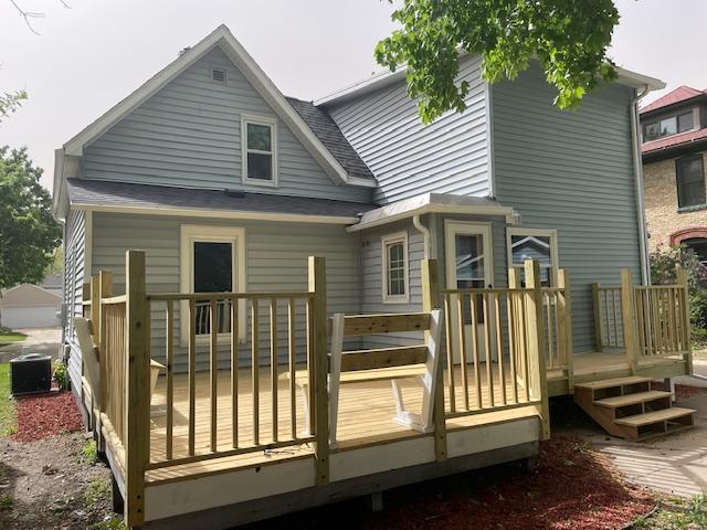 rear view of property featuring a wooden deck and central AC unit