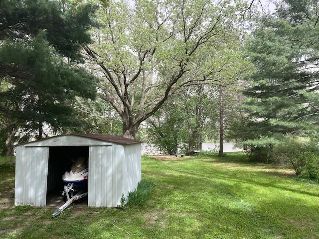 view of grassy yard featuring a storage unit and an outbuilding