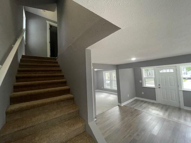 foyer with wood finished floors, stairway, and a textured ceiling