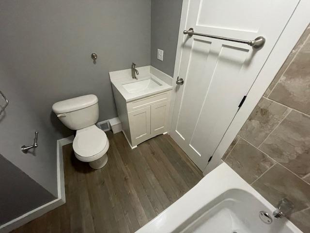 bathroom with toilet, wood finished floors, a shower, vanity, and a bath