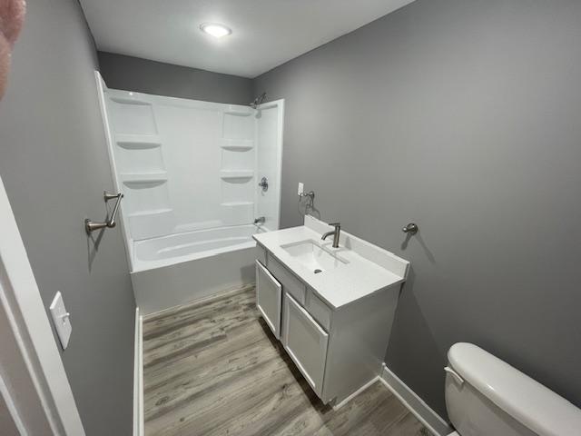 full bathroom featuring wood finished floors, toilet, vanity, and  shower combination