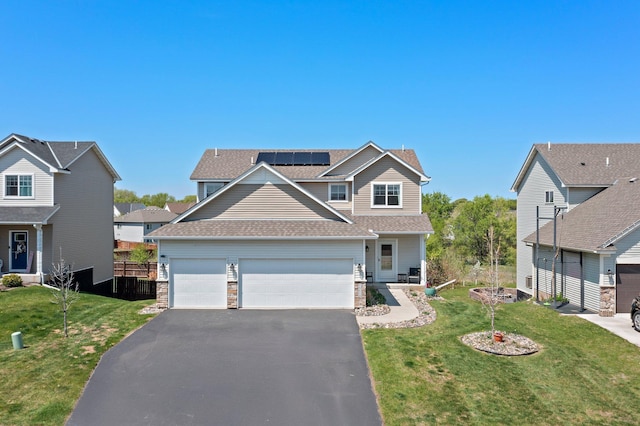 view of front of house with roof mounted solar panels, driveway, a garage, roof with shingles, and stone siding