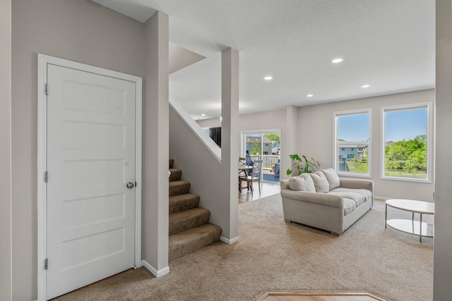 carpeted living area featuring stairway, baseboards, and recessed lighting