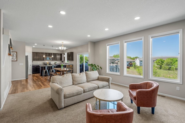 living room featuring light colored carpet, baseboards, recessed lighting, a chandelier, and a textured ceiling