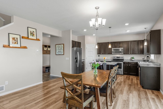 dining space featuring a chandelier, light wood-style floors, baseboards, and recessed lighting