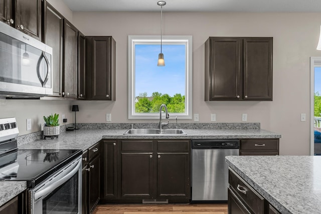 kitchen featuring appliances with stainless steel finishes, a sink, healthy amount of natural light, and pendant lighting