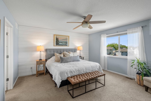 carpeted bedroom featuring baseboards, a textured ceiling, a ceiling fan, and wooden walls