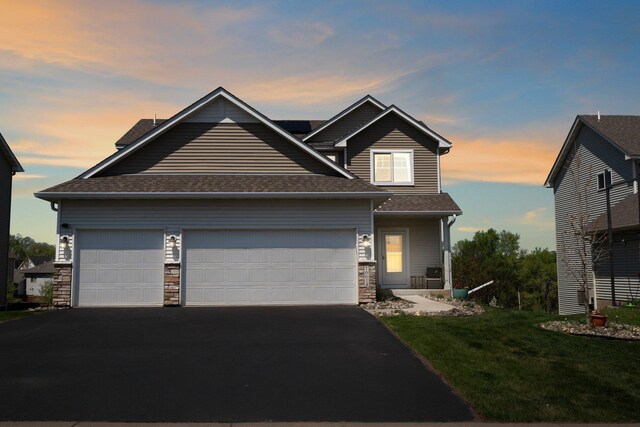view of front of home featuring asphalt driveway, a garage, and a shingled roof