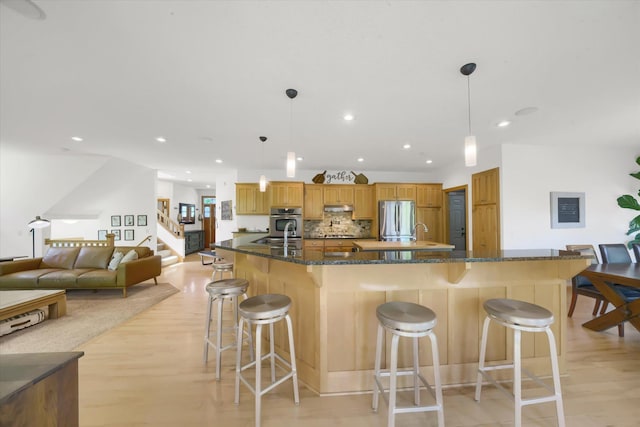 2907 Cougar Path NW, Prior Lake, MN 55372 - kitchen with appliances with stainless steel finishes, a kitchen bar, light wood finished floors, under cabinet range hood, and recessed lighting