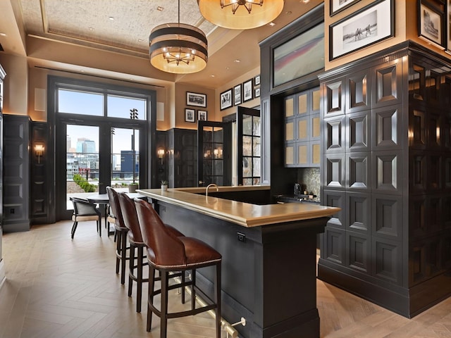 1111 River Pkwy Unit 33A, Minneapolis, MN 55415 - bar area with a chandelier, a raised ceiling, pendant lighting, and tasteful backsplash
