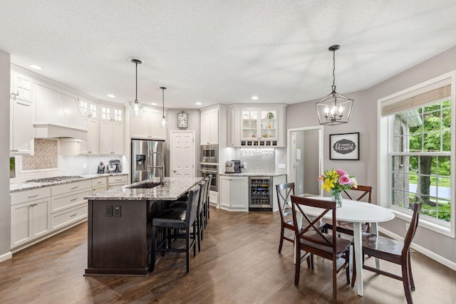 18764 Farmstead Cir, Eden Prairie, MN 55347 - kitchen featuring appliances with stainless steel finishes, beverage cooler, a sink, backsplash, and custom exhaust hood