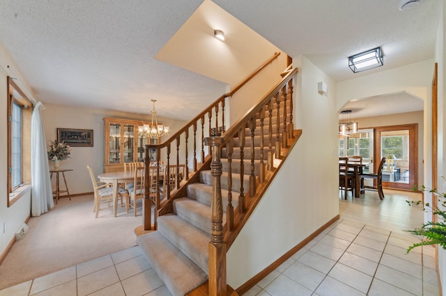 4975 Maribe Dr, Hermantown, MN 55811 - stairs with tile patterned flooring, a chandelier, a textured ceiling, baseboards, and carpet
