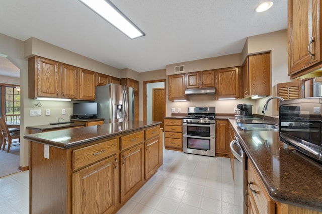 4975 Maribe Dr, Hermantown, MN 55811 - kitchen with appliances with stainless steel finishes, a sink, under cabinet range hood, brown cabinets, and a center island