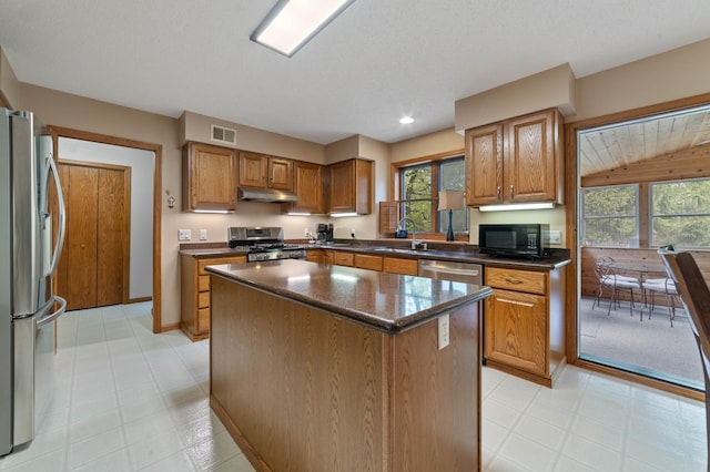 4975 Maribe Dr, Hermantown, MN 55811 - kitchen featuring stainless steel appliances, under cabinet range hood, a sink, brown cabinets, and a center island