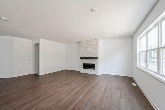 7353 Auburn Ln, Inver Grove Heights, MN 55077 - unfurnished living room featuring dark wood-style floors, a stone fireplace, baseboards, and a textured ceiling