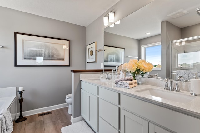 7353 Auburn Ln, Inver Grove Heights, MN 55077 - full bathroom featuring double vanity, toilet, a shower stall, wood finished floors, and baseboards