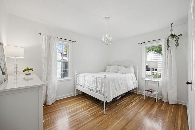 bedroom with light wood finished floors, a chandelier, and baseboards