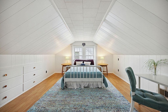 bedroom with baseboards, wood finished floors, and lofted ceiling