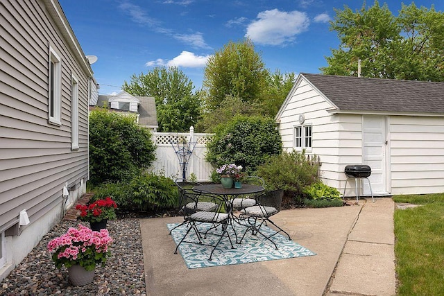 view of patio featuring fence, an outbuilding, outdoor dining space, and a shed
