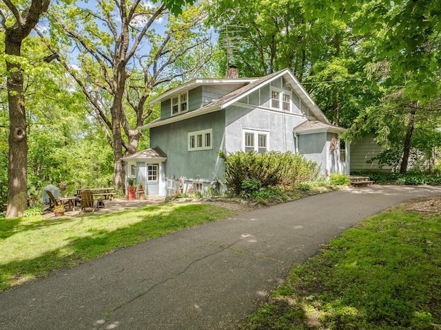 15210 Mckenzie Blvd, Minnetonka, MN 55345 - view of front of property featuring a chimney, stucco siding, a front lawn, and a patio