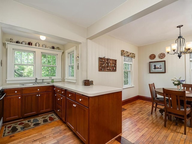 15210 Mckenzie Blvd, Minnetonka, MN 55345 - kitchen featuring a sink, light wood-style flooring, a chandelier, light countertops, and hanging light fixtures