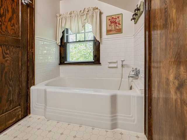 15210 Mckenzie Blvd, Minnetonka, MN 55345 - bathroom with tile patterned floors, a bath, a wainscoted wall, and tile walls