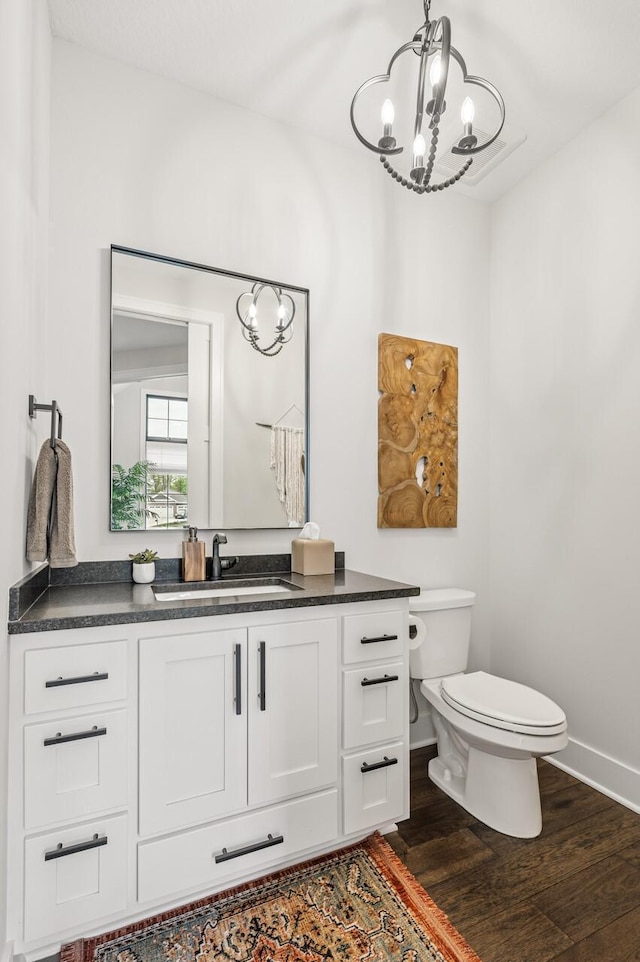 202 176th Ln NE, Ham Lake, MN 55304 - half bathroom featuring a chandelier, wood finished floors, toilet, baseboards, and vanity