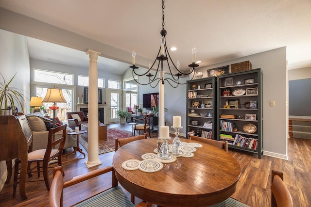 2513 Aspen Ln SW, Rochester, MN 55902 - dining area featuring decorative columns, wood finished floors, a chandelier, a fireplace, and baseboards