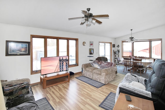 living room featuring a ceiling fan, vaulted ceiling, light wood-style flooring, and baseboards