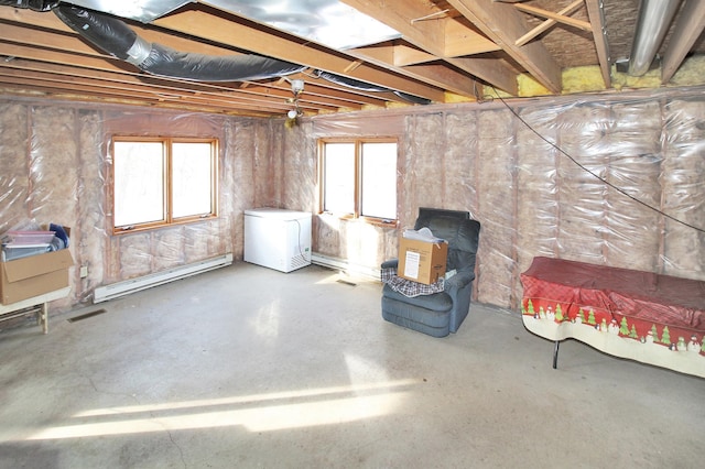 basement featuring a baseboard heating unit, refrigerator, and plenty of natural light