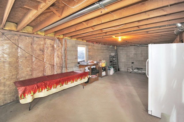 basement featuring freestanding refrigerator and a wood stove