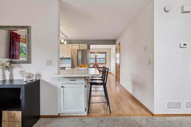 1039 Briar Creek Rd, Eagan, MN 55123 - kitchen with freestanding refrigerator, a peninsula, a textured ceiling, light countertops, and a chandelier