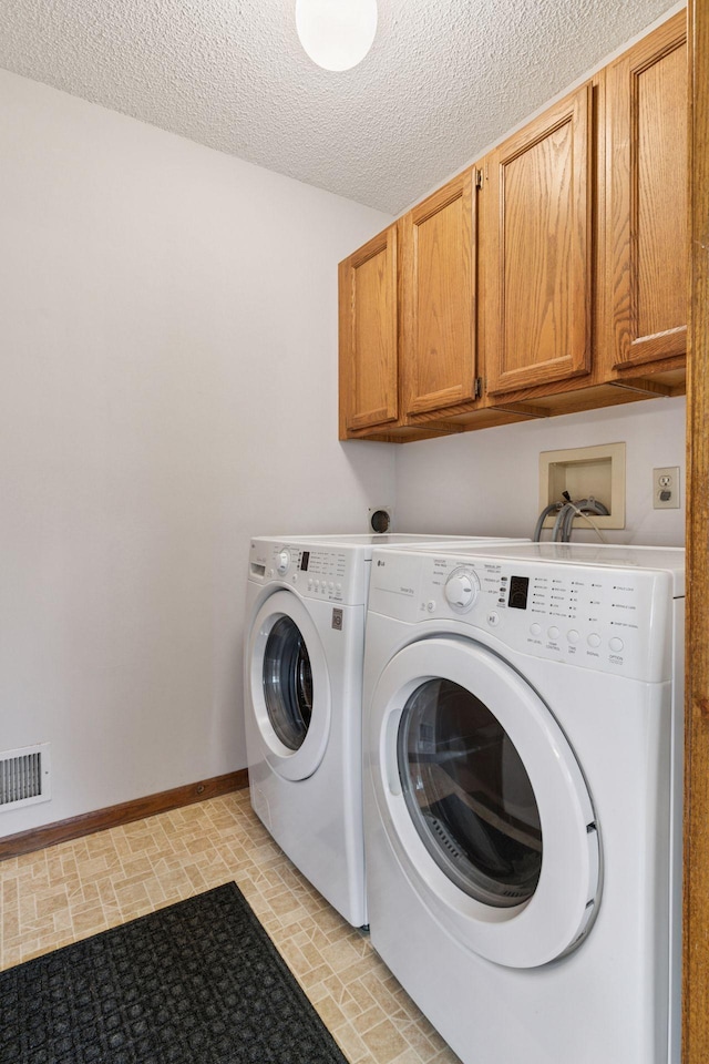 1039 Briar Creek Rd, Eagan, MN 55123 - laundry area featuring cabinet space, washing machine and clothes dryer, baseboards, and a textured ceiling