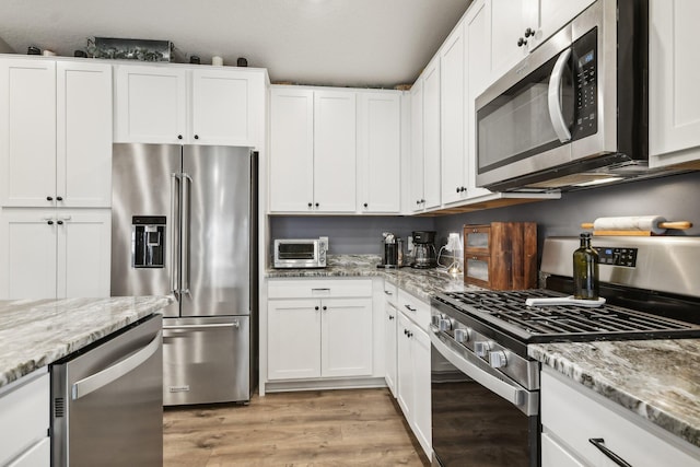 7516 Ochoa Ave NE, Otsego, MN 55330 - kitchen with appliances with stainless steel finishes, light wood finished floors, white cabinetry, and light stone counters