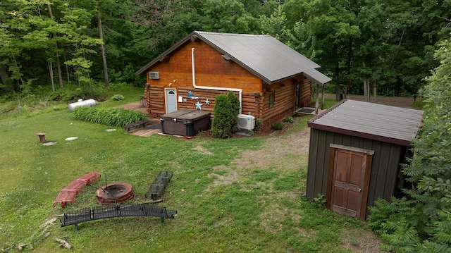 17377 Paradise Shores Rd, Maple Grove Twp, MN 56401 - back of house with a hot tub, an outdoor fire pit, log exterior, a lawn, and an outdoor structure